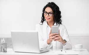 Portrait of busy hispanic woman using cellphone and computer