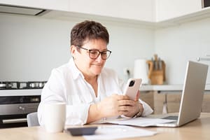 Happy senior woman using mobile phone while working at home