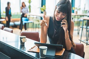 Cafe city lifestyle woman drinking coffee talking on a cell phone using her ipad