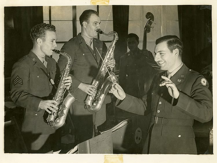 CWO Frank Rosato conducting three 156th Infantry musicians playing saxophones and bass.