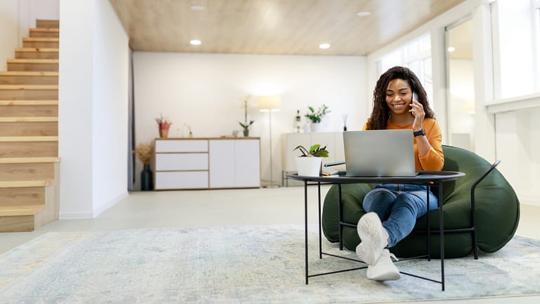 Smiling black woman working and talking on phone at home