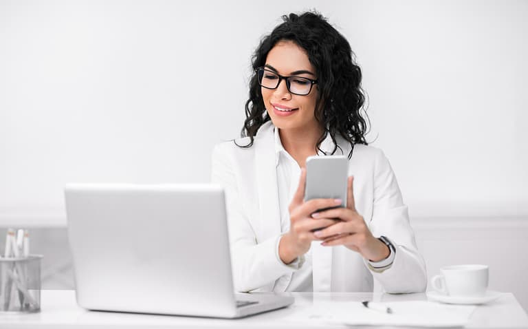 Portrait of busy hispanic woman using cellphone and computer
