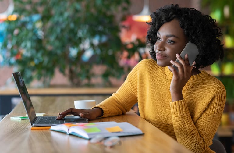 Young black businesswoman having conversation with clients on phone